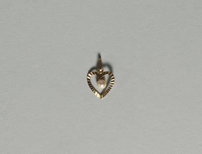 un gros plan d'un pendentif en forme de cœur avec une perle au centre