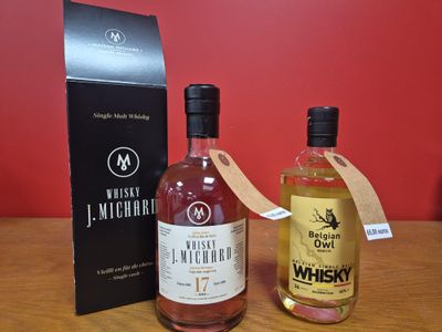 deux bouteilles de whisky posées sur une table à côté d'une boîte noire