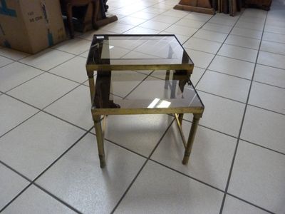une table basse en verre et en laiton posée sur un sol carrelé