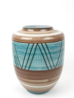 un vase bleu et brun posé sur une surface blanche