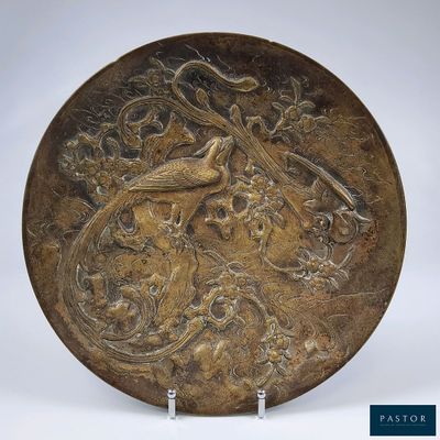 une plaque en bronze ornée d'un oiseau et de fleurs