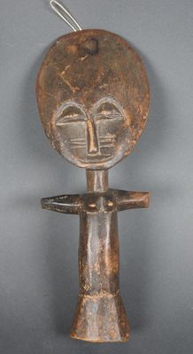 une vieille figurine en bois avec un visage sur la tête