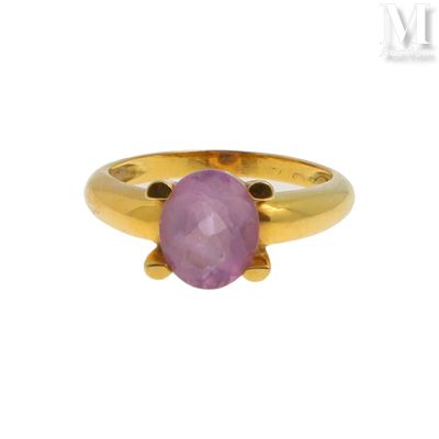 gros plan d'une bague en or avec une pierre rose