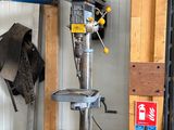 une perceuse à colonne dans un garage, avec un chat assis à côté