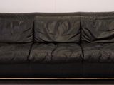 a black leather couch sitting in a corner of a room