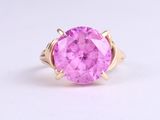 a close up of a pink stone ring on a white surface