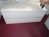 a white chest of drawers in the corner of a room