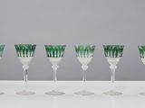 six green and white wine glasses lined up on a table
