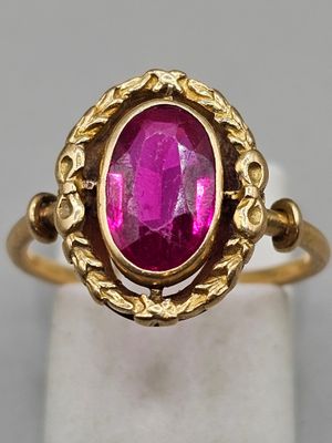 a close up of a gold ring with a pink stone in it