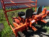 un tracteur rouge avec un siège noir, garé dans l'herbe