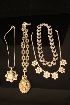 three necklaces and a pendant are displayed on a black surface
