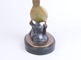 a figurine of a cat holding a pear on its head