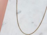 un collier à chaîne en or posé sur une surface en marbre