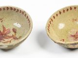 pair of small bowls with floral designs on them on a white surface