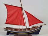 wooden model of a sailboat with red sails on a white background