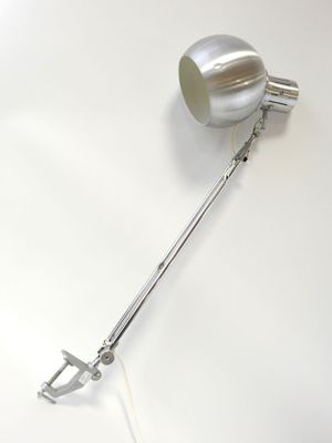 une lampe en argent posée sur une table blanche
