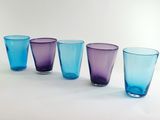 four different colored glasses are lined up in a row on a white surface