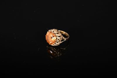 un gros plan d'une bague posée sur une surface noire, avec un fond noir