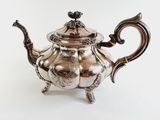 an antique silver teapot with a bird on top of it