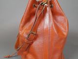 an orange leather bucket bag sitting on top of a gray surface