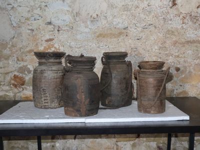cinq vases posés sur une table devant un mur de pierre