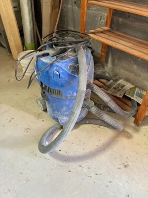 un aspirateur bleu posé par terre dans une pièce