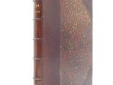 un vieux livre à la couverture brune posé sur une surface blanche