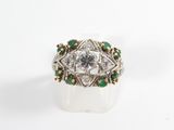 a close up of a diamond and emerald ring on a white surface