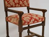 une image représentant une chaise dont l'assise est recouverte d'un tissu rouge et doré
