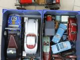 two blue boxes with toy cars in them on a tile floor
