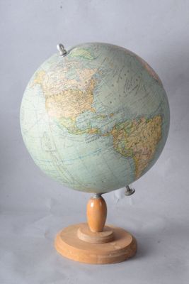 un petit globe terrestre posé sur un socle en bois, sur fond blanc
