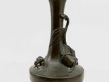 un vase noir orné d'un oiseau sur fond blanc