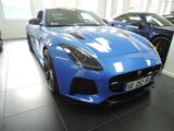 une voiture de sport bleue dans un showroom, aux côtés d'autres voitures