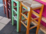 Dans un restaurant, des tabourets aux couleurs vives sont alignés contre un mur rose.