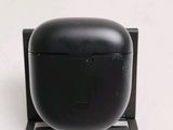 a black airpods sitting on a stand on a white surface