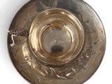 a silver plate with a bird on it on a white surface