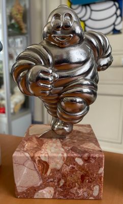 une statue représentant un homme tenant un poisson, posée sur un socle en marbre