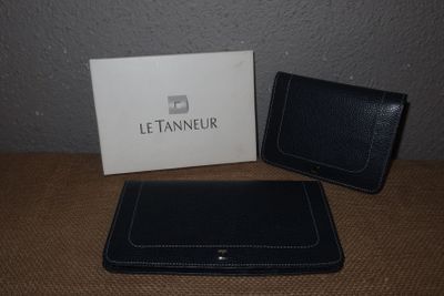 un portefeuille et un porte-cartes en cuir noir posés sur une table à côté d'une boîte blanche