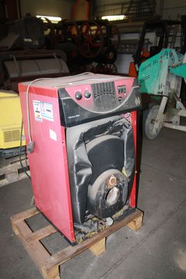 a red machine sitting on a pallet in a garage