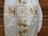 un gilet blanc orné d'une croix dorée, accroché à un mur en bois