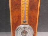une horloge en bois à l'ancienne, équipée d'un thermomètre