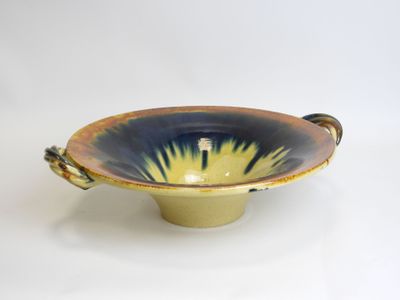 a blue and yellow bowl with handles on a white surface