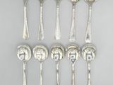 six silver spoons and two silver spoons on a gray surface
