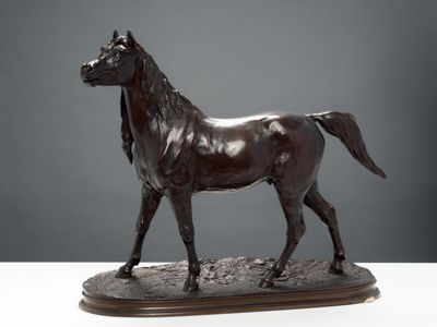 statue en bronze représentant un cheval, posée sur un socle en bois, elle-même posée sur une table