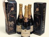 three bottles of champagne and a box of chocolates on a white surface