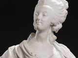 white marble bust of a woman with a shawl around her neck