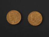 two gold coins on a black surface with a black background