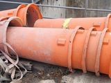 a pile of orange pipes on the ground next to a fence