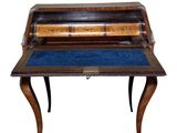an old writing desk with a blue velvet pad on top of it