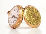 a close up of a gold pocket watch with roman numerals on it